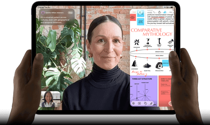 iPad Pro, pohled zepředu, orientace na šířku, vesmírně černá barva, zaoblené rohy, černý rámeček displeje, ruce drží levou a pravou stranu, na displeji se zobrazuje FaceTime konverzace překládaná v reálném čase a vzdělávací aplikace s prezentací na téma komparativní mytologie, textem, diagramy a ručně psanými poznámkami